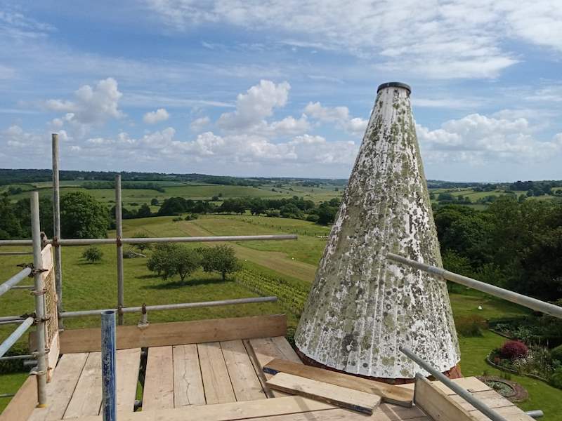 Oast house roof restoration with scaffolding and countryside views